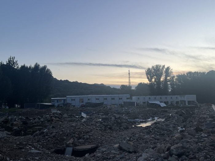 村委会附近一工地宿舍被冲毁，板房前堆满了石块和淤泥