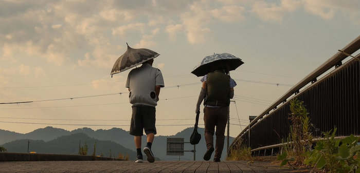 当地时间2025年7月30日，日本兵库县丹波篠山市，一人们在酷热天气中撑伞过桥。