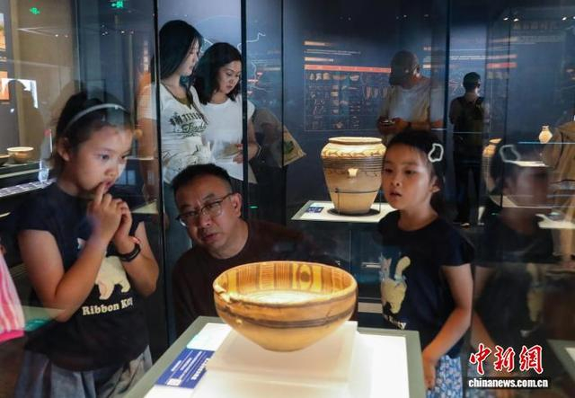 8月3日，青海西宁，家长给孩子讲解宗日遗址出土的马家窑类型双人抬物纹彩陶盆。中新社记者 马铭言 摄 