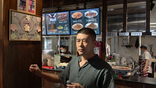 8月3日，呼和浩特古麦优品兰州牛肉面负责后勤的王高翔在介绍爱心便签板。 澎湃新闻记者 王岱玉 图