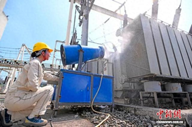图为国网重庆市北供电公司运维人员在220千伏大竹林变电站用水炮对变压器进行降温。向江微 摄