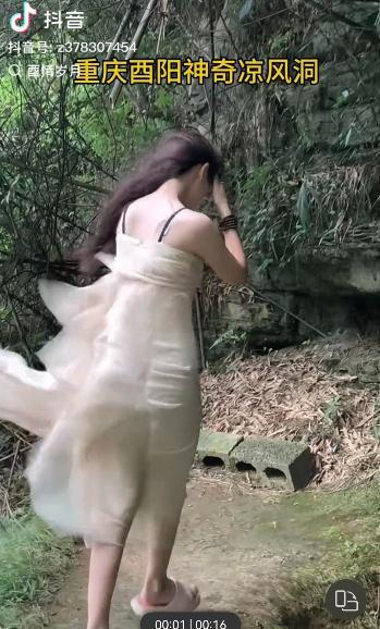一女士在洞口衣服和头发被吹乱 图据网友“酉情岁月”的视频截图