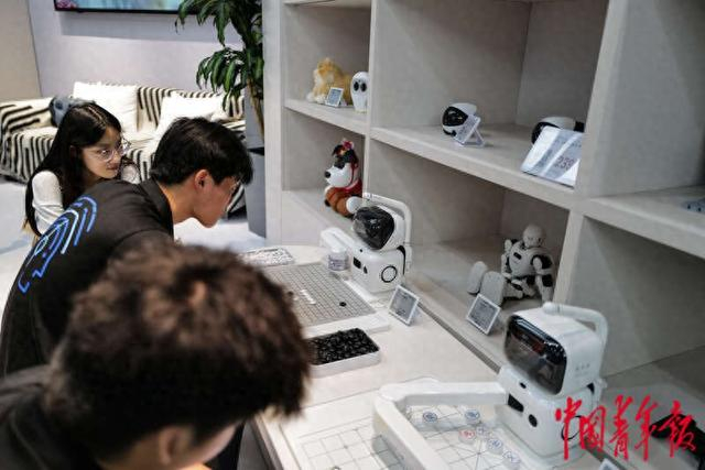 8月6日，北京亦庄，具身智能机器人4S店一层，媒体记者体验与机器人下象棋。中青报·中青网记者 赵迪/摄