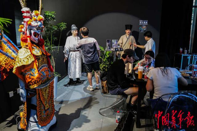 8月6日，北京亦庄，机器人焰究所内，提前体验餐食的记者身后有几位“气氛组”机器人在表演。中青报·中青网记者 赵迪/摄