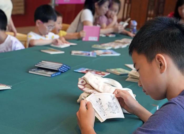 7月16日,在上海市群众艺术馆的“走进艺术之门”系列活动中,孩子们在阅读角看连环画。新华社记者 刘颖 摄