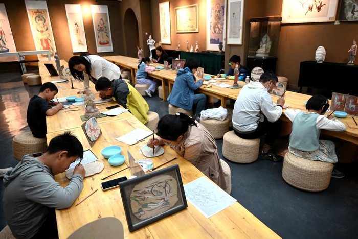2025年5月4日，游客在甘肃省敦煌小镇研学课堂上学习临摹敦煌壁画。新华社发（张晓亮摄）