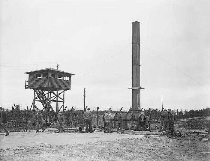 1945年9月17日,德国下萨克森州,参观者在卑尔根-贝尔森集中营检查焚尸炉。左侧是一个警卫小屋。图源:视觉中国