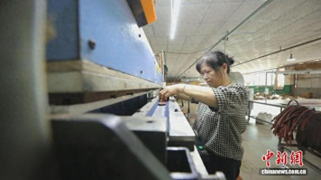 伍金花在工位上操作机械进行皮带压花。安仁县委宣传部供图