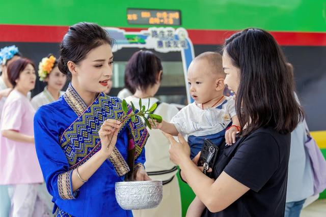 7月18日，在昆明站，昆明至万象D86次列车乘务员向乘车旅客洒水表达祝福。新华社发（陈畅摄）