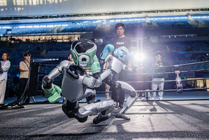 宇树工作人员在比赛开始之前对参赛队员进行机器人搏击训练 新京报记者王子诚/摄