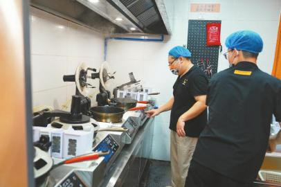 在成都秋金川味小炒后厨，工作人员熟练地操作着炒菜机器人。