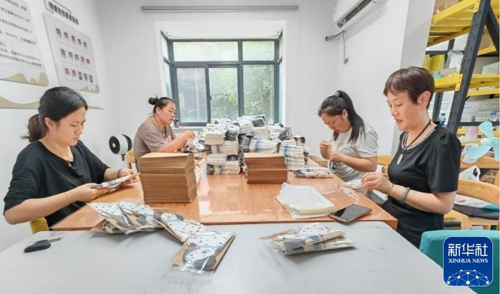 在“禹邻工坊”里，“宝妈”们专注地折叠着纸巾。新华社客户端发（詹燕南 摄）