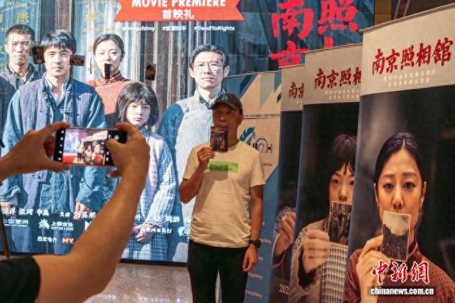 观影民众在海报前拍照留念。 记者 陈悦 摄