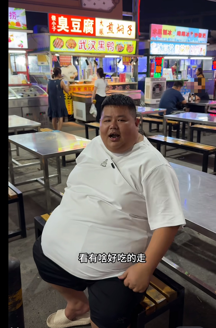8月19日的视频中，良子来到夜市吃东西，他坐下时突出的肚子几乎跟膝盖齐平。良子直播间视频截图