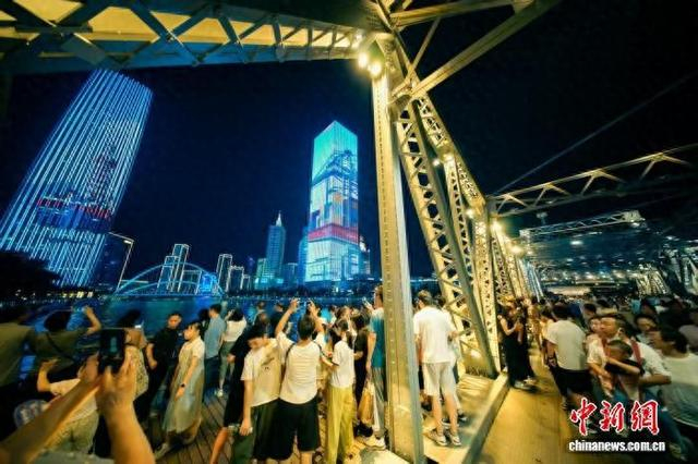 8月28日，天津海河解放桥畔，市民和游客拍摄上合主题光影秀。中新社记者 佟郁 摄