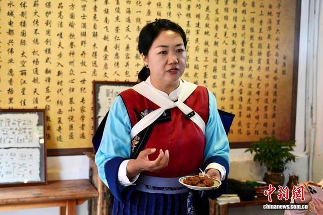 8月11日，和育苗向游客展示纳西族传统婚礼美食。罗婕 摄
