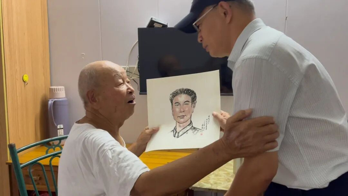 张钟（右）将陈纪先烈士的画像交到陈其安（左）手中