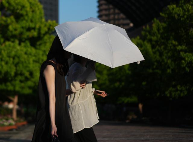 6月18日,在日本东京,行人撑伞在街头行走。新华社记者贾浩成摄
