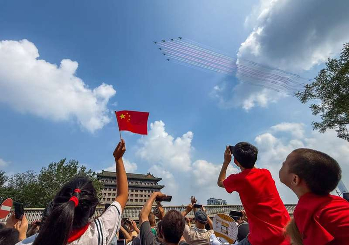 ▲9月3日上午，在北京东便门，市民挥舞国旗欢迎空中受阅方队飞过。新京报记者 王贵彬 摄