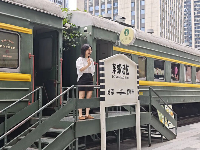 游客在铁轨上的绿皮火车咖啡厅前打卡拍照