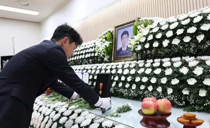韩国总统秘书室长姜勋植在牺牲海警灵前摆放勋章 图源：韩联社