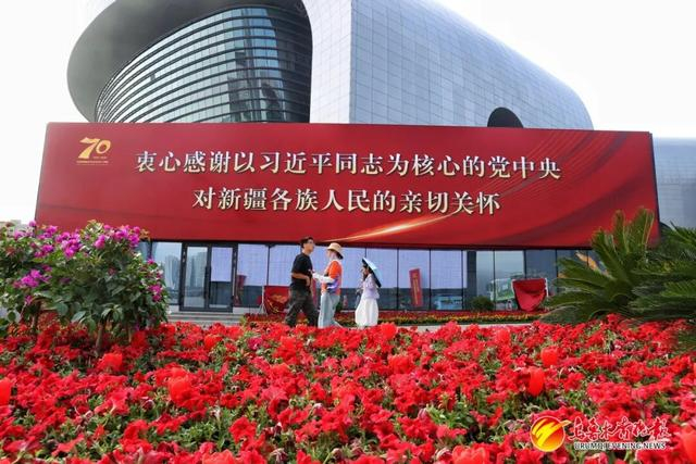 乌鲁木齐文化中心印有新疆维吾尔自治区成立70周年庆祝标语的展板。 