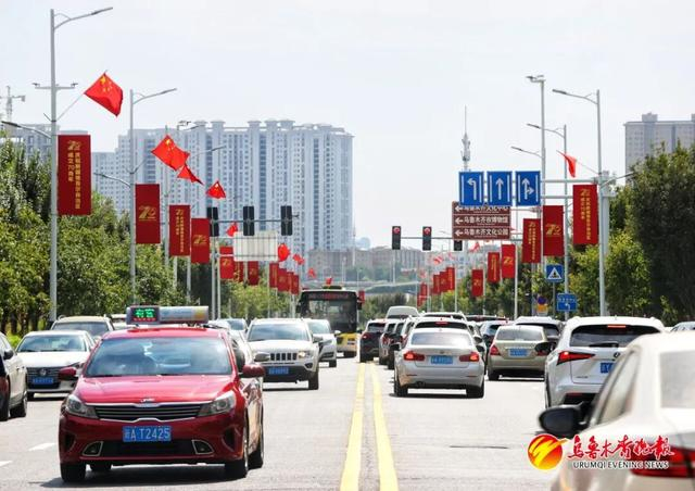 会展南路道路两侧悬挂的五星红旗和印有新疆维吾尔自治区成立70周年庆祝活动标识的道旗。