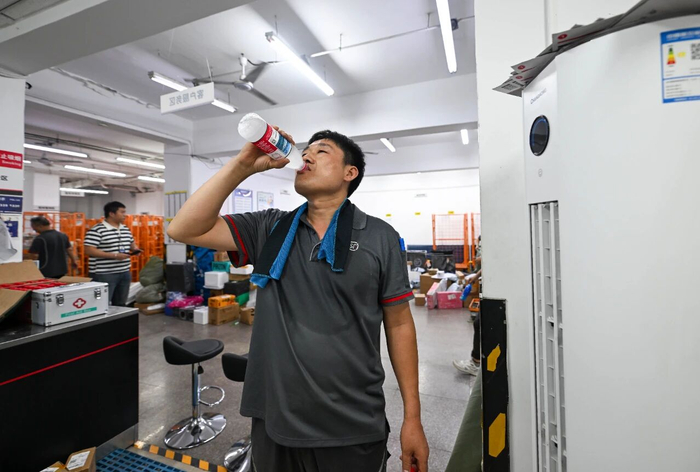 一名快递小哥在天津市河西区一处快递站点内补水降温 赵子硕 摄