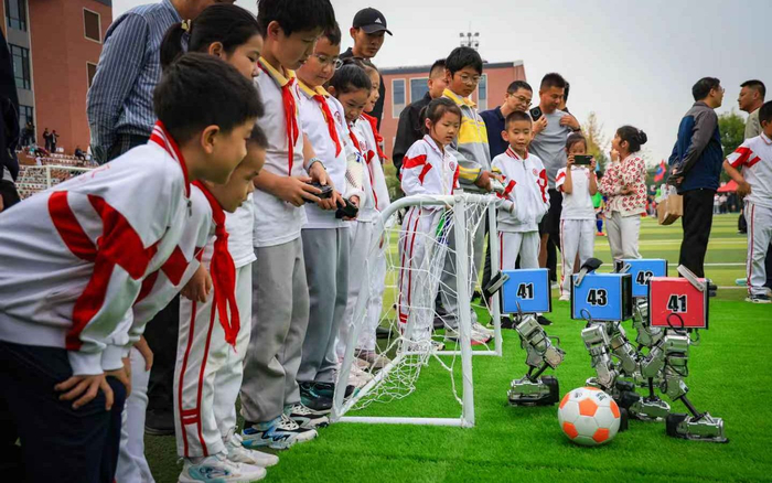 小学生们给赛场内的机器人足球队员加油助威。 新京报记者王远征 摄