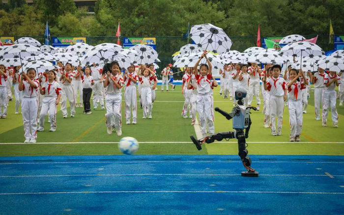 孩子们撑开手中足球图案的雨伞，和机器人同场表演。 新京报记者王远征 摄
