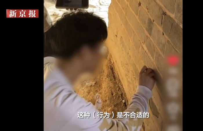 当事人在长城上刻画被其他游客拍下。新京报我们视频截图