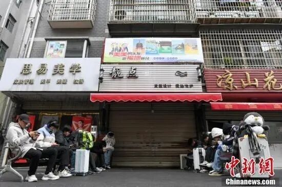 2025年1月8日，众多外地顾客提着行李箱等待李晓华的理发店开门。中新社记者 杨华峰 摄