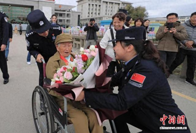 10月7日，在吉林图们口岸，移民管理警察为金虎月老人送上鲜花。张彪 摄