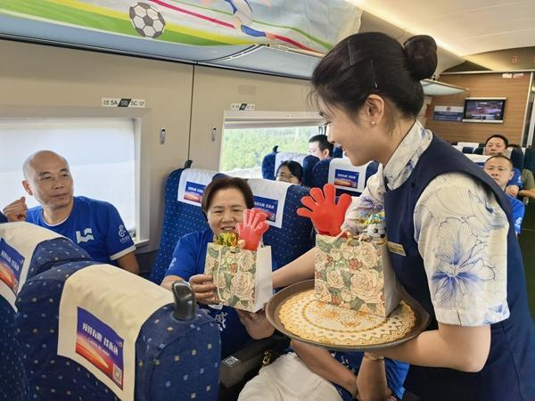 10月4日，列车乘务员给“球迷专列”旅客发放观赛“助威包”。王梦婧子/摄