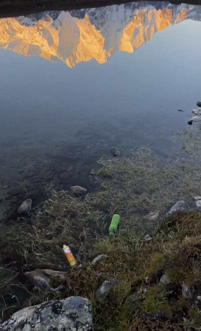 今年“十一”前后，倒映着日照金山的湖边零星散落着塑料瓶。受访者供图
