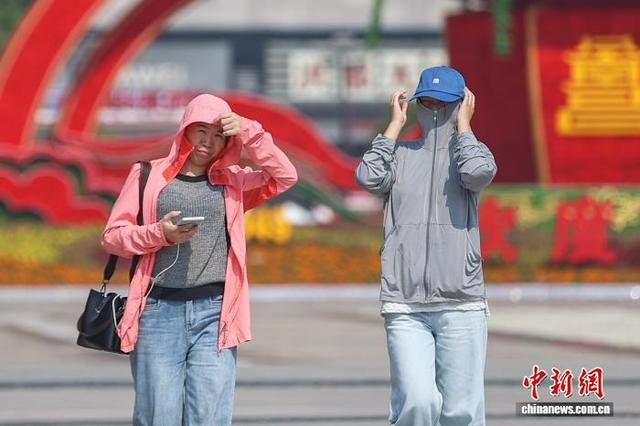 10月11日，江西南昌，民众身穿防晒衣戴帽子出行。中新社记者 刘力鑫 摄