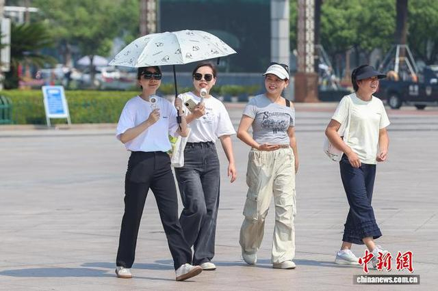 10月11日，江西南昌，民众撑伞、手拿小风扇出行。中新社记者 刘力鑫 摄
