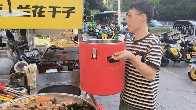 △黎先生将装有兰花干的桶搬到摊位，两个多小时，共售出三桶兰花干。图/史继超摄