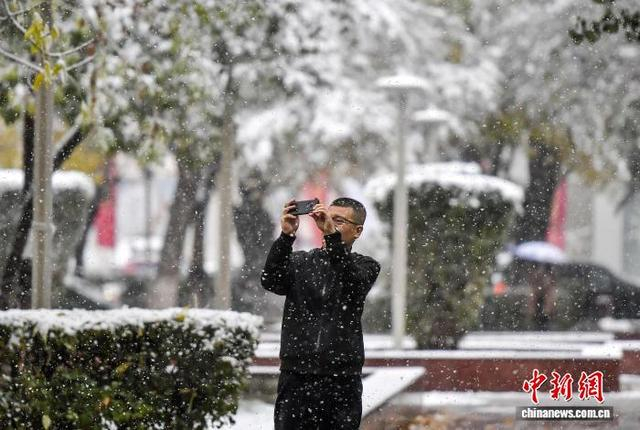 10月15日，新疆乌鲁木齐市降下皑皑白雪，市民用手机拍照。中新社记者 刘新 摄