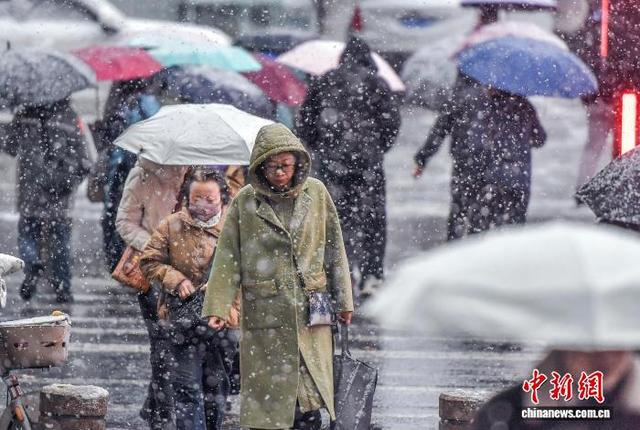 10月15日，新疆乌鲁木齐市降下皑皑白雪，市民在雨雪天气中出行。中新社记者 刘新 摄