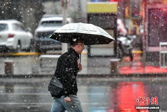 10月15日，新疆乌鲁木齐市降下皑皑白雪，市民在雨雪天气中出行。中新社记者 刘新 摄