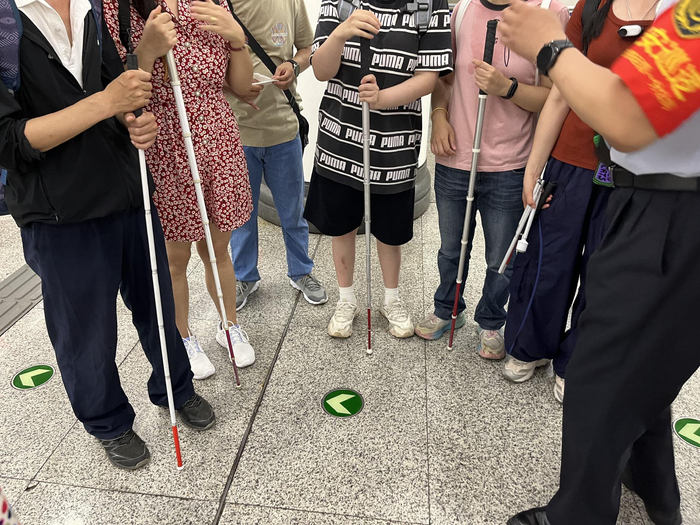 学员们拿着盲杖，在工作人员的帮助下乘坐地铁。新京报记者 徐鸣 摄