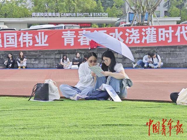 双选活动现场，两名学生一起讨论岗位信息。石晶/摄