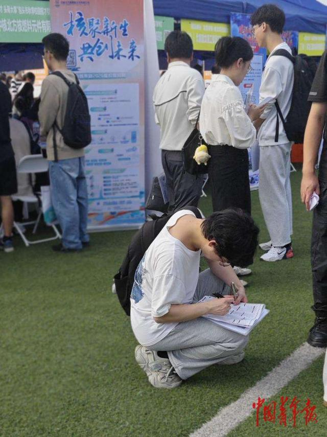 10月16日，重庆大学双选活动现场，一名学生在参会单位一览表上标记岗位信息。石晶/摄