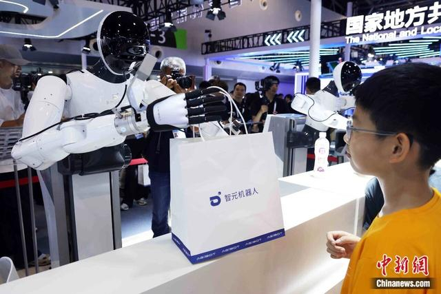 2025年7月26日，2025世界人工智能大会在上海开幕。图为机器人分发产品资料。中新社记者 汤彦俊 摄