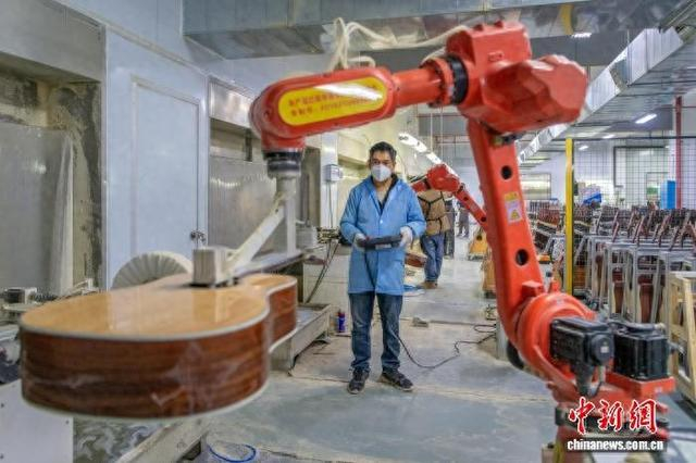 在东安，吉他企业的工人正在操控机械臂打磨吉他。蔡小平 摄