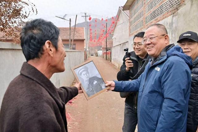 11月5日，新华社记者于力（右二）向杨忠贵烈士侄（左）展示照片修复效果。新华社记者 吴青昊 摄