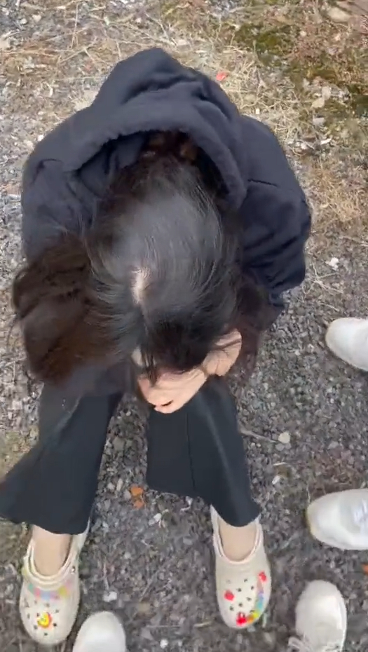 截图自网传视频，同行黑衣女子坐在地上埋着头。