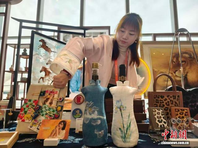 昌妮携手蜡染扎染非遗代表性传承人冯灿制作的刺绣旗袍红酒套亮相第七届中法文化论坛非遗展。中新网记者 唐小晴 摄