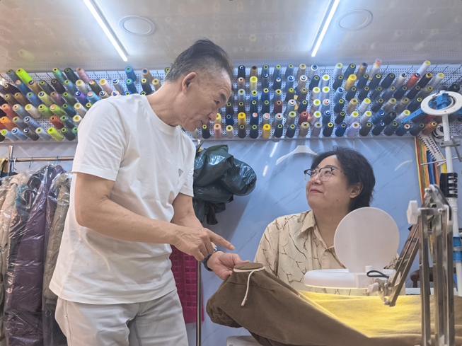 ▲徐春元（左）指导徒弟殷玥（右）修补衣物